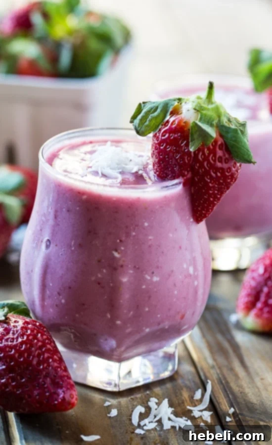 Close-up of Strawberry Coconut Smoothie garnished with fresh strawberries and shredded coconut
