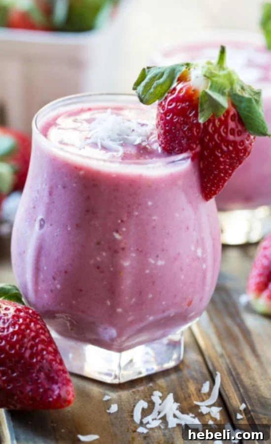 Strawberry Coconut Smoothie poured into a glass with a straw