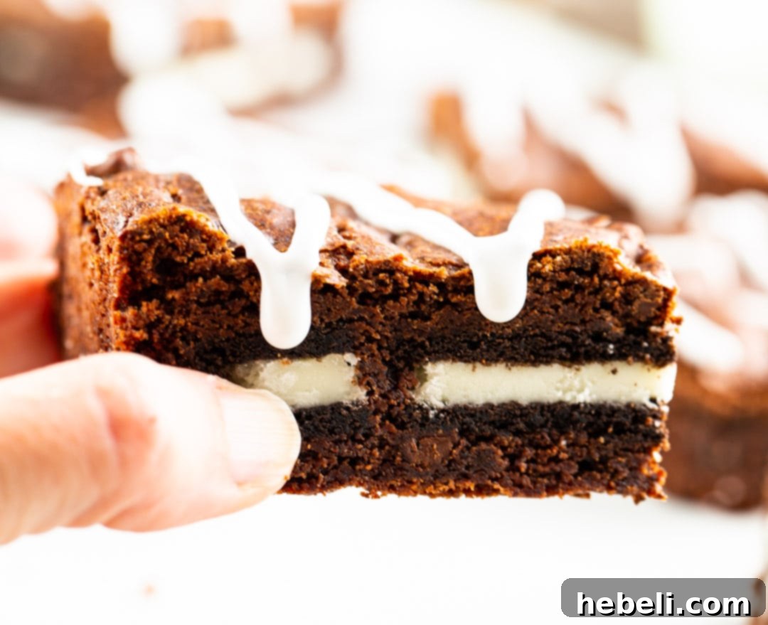 A hand reaching for a piece of Oreo Stuffed Brownie, highlighting the tempting nature of this sweet treat.