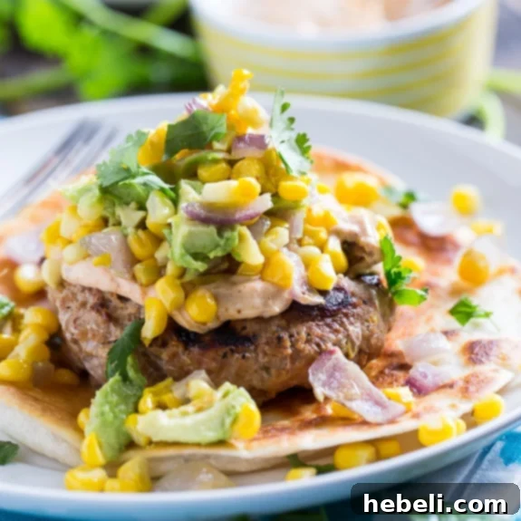 Close-up of a Tex-Mex Turkey Burger on a crispy tortilla with avocado corn salsa and spicy mayo