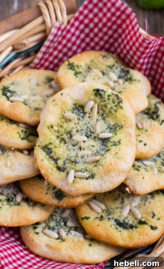 Mini Focaccia Bites 3 Close-up of freshly baked Biscuit Mini Focaccia rounds, highlighting the golden edges and the rich green pesto, cheese, and pine nut topping. Perfect for a quick snack or appetizer.