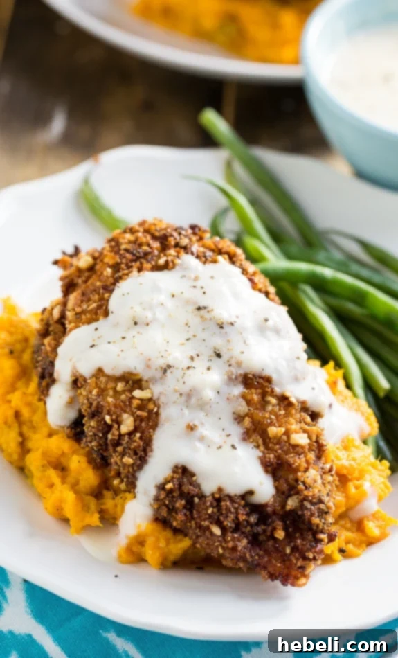 Nutty Fried Chicken with Smashed Sweet Potatoes and Milk Gravy, served with a green side dish.