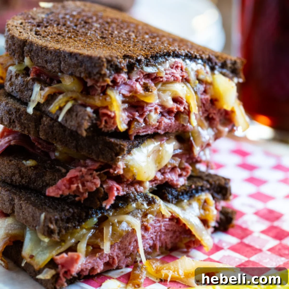 The Sizzling Corned Beef Melt 2 Two halves of a Corned Beef Grilled Cheese sandwich, stacked, revealing the melted cheese, corned beef, and caramelized onions.