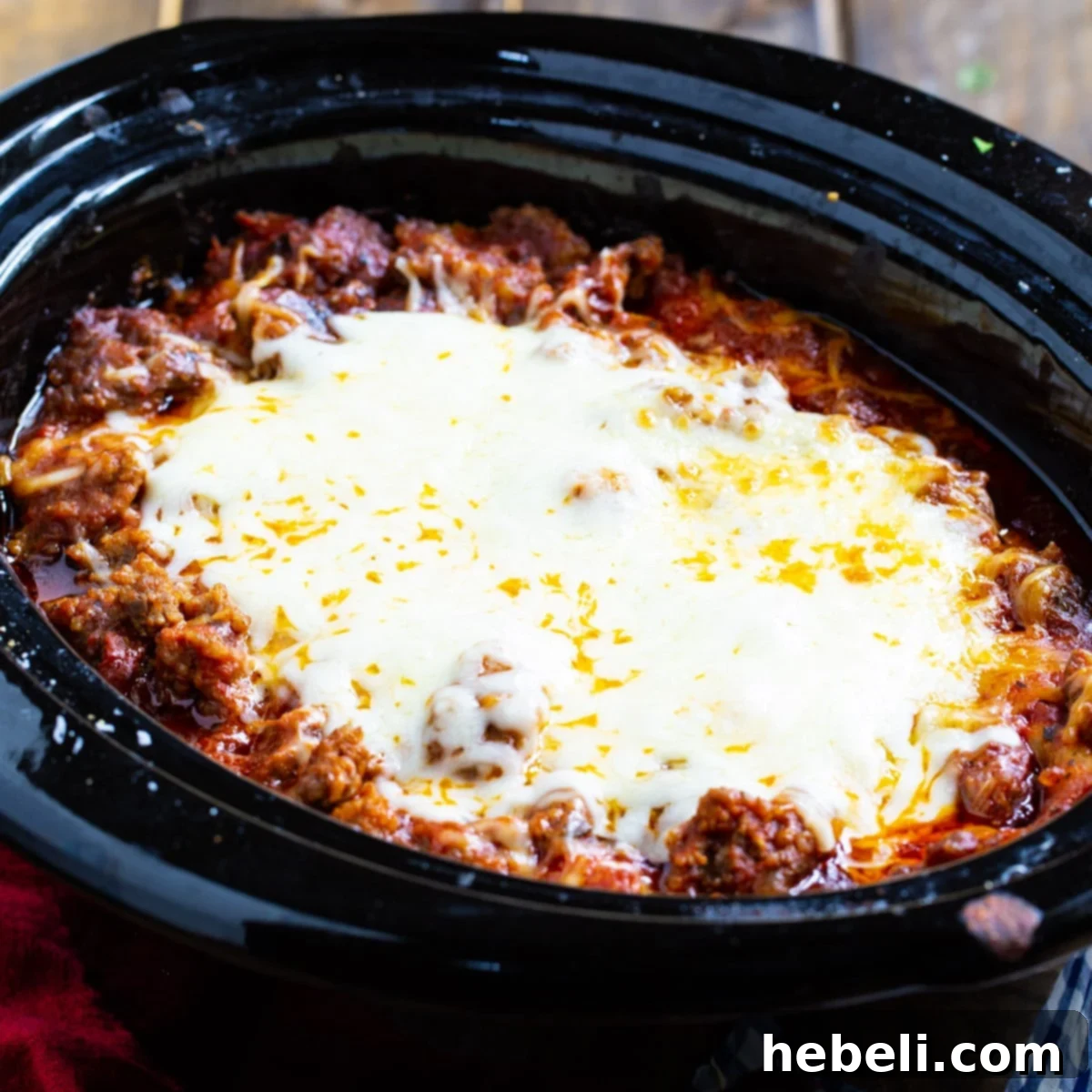 A perfectly cooked slow cooker lasagna in a black crockpot, ready to be served.