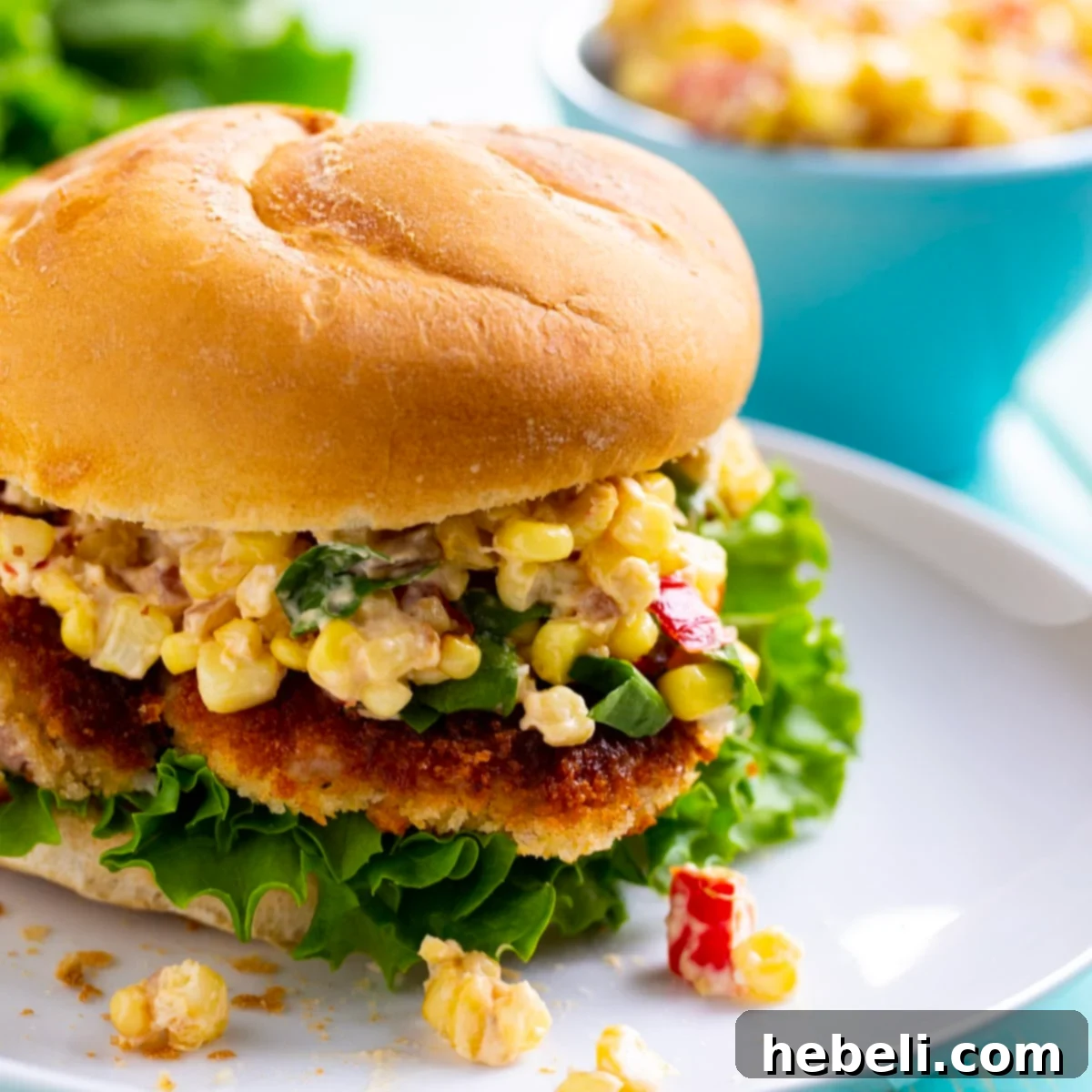 Hoosier Pork Tenderloin Sandwich 2 Crispy Indiana Pork Tenderloin Sandwich served on a plate with a side of creamy corn relish, garnished with fresh herbs.