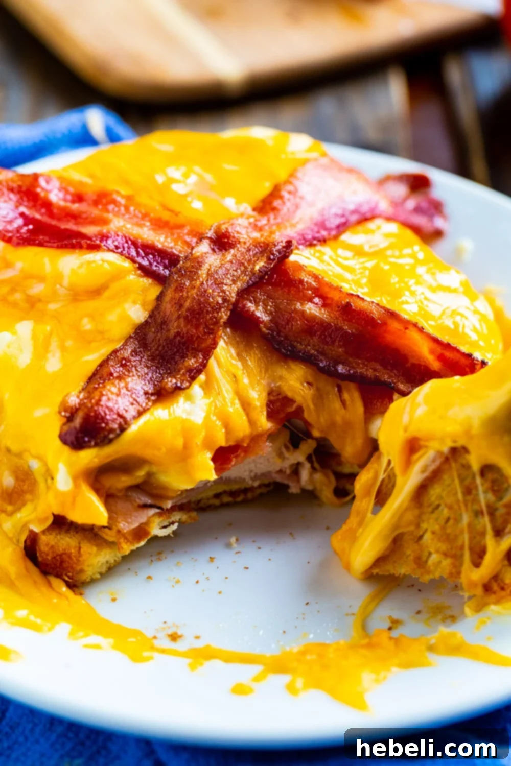 A slice cut out of a perfectly cooked Kentucky Hot Brown Sandwich, revealing layers of turkey, ham, gravy, and cheese.