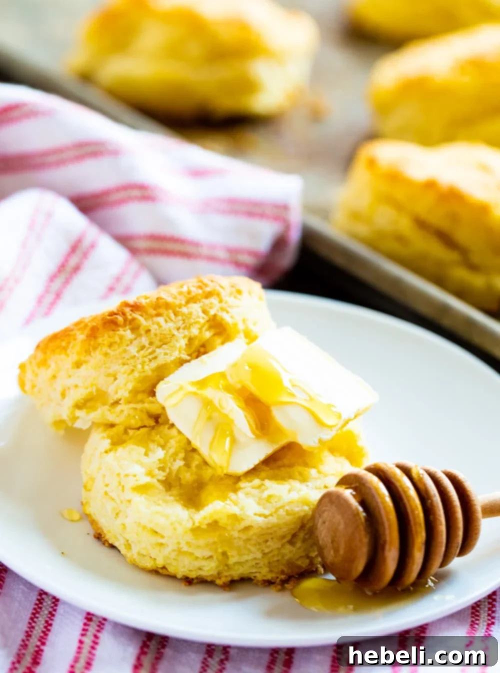 A warm Tupelo Honey Ginormous Biscuit split open, slathered with butter and drizzled with golden honey, ready to be enjoyed.