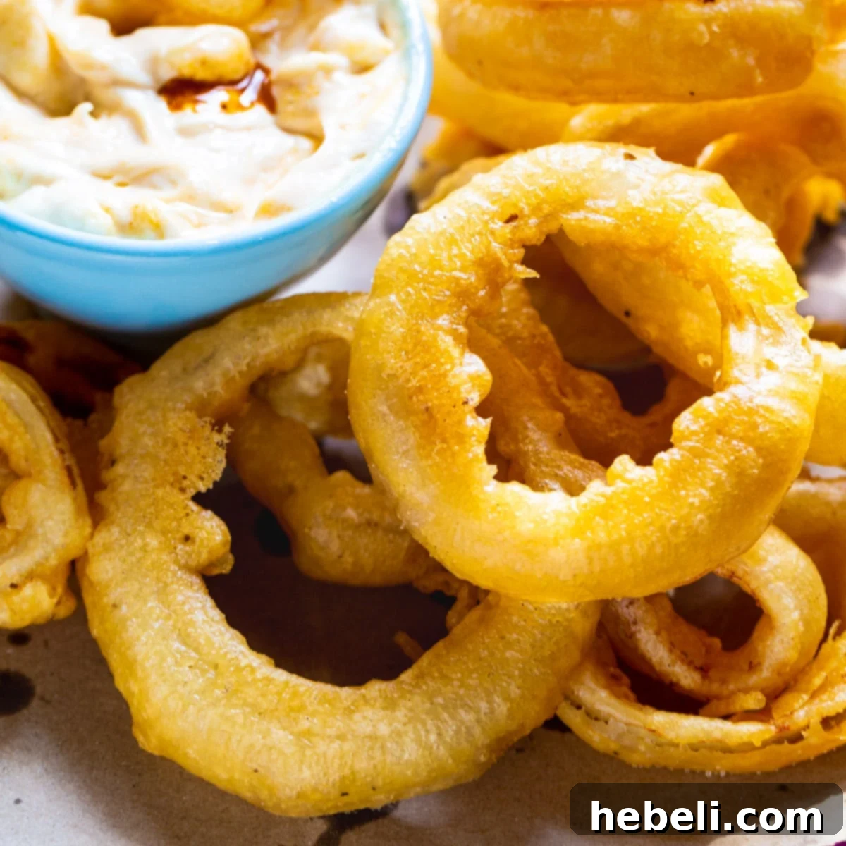 Perfectly Crispy Beer Onion Rings 2 Beer Battered Onion Rings on a plate with dipping sauce.