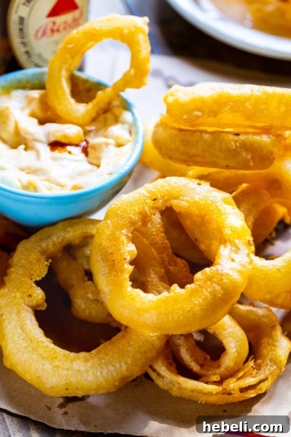 Perfectly Crispy Beer Onion Rings 3 Crispy Beer Battered Onion Rings on a plate with a bowl of homemade curry dipping sauce.