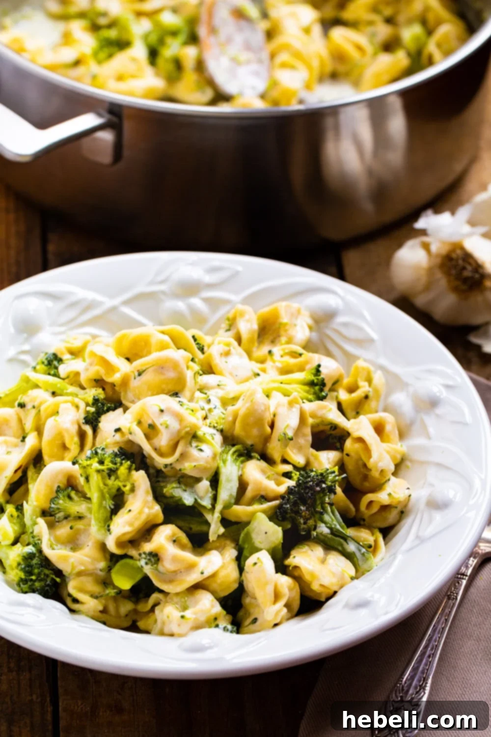 A bowl of Broccoli Alfredo Tortellini, perfectly dished up and ready to enjoy, garnished with fresh Parmesan.