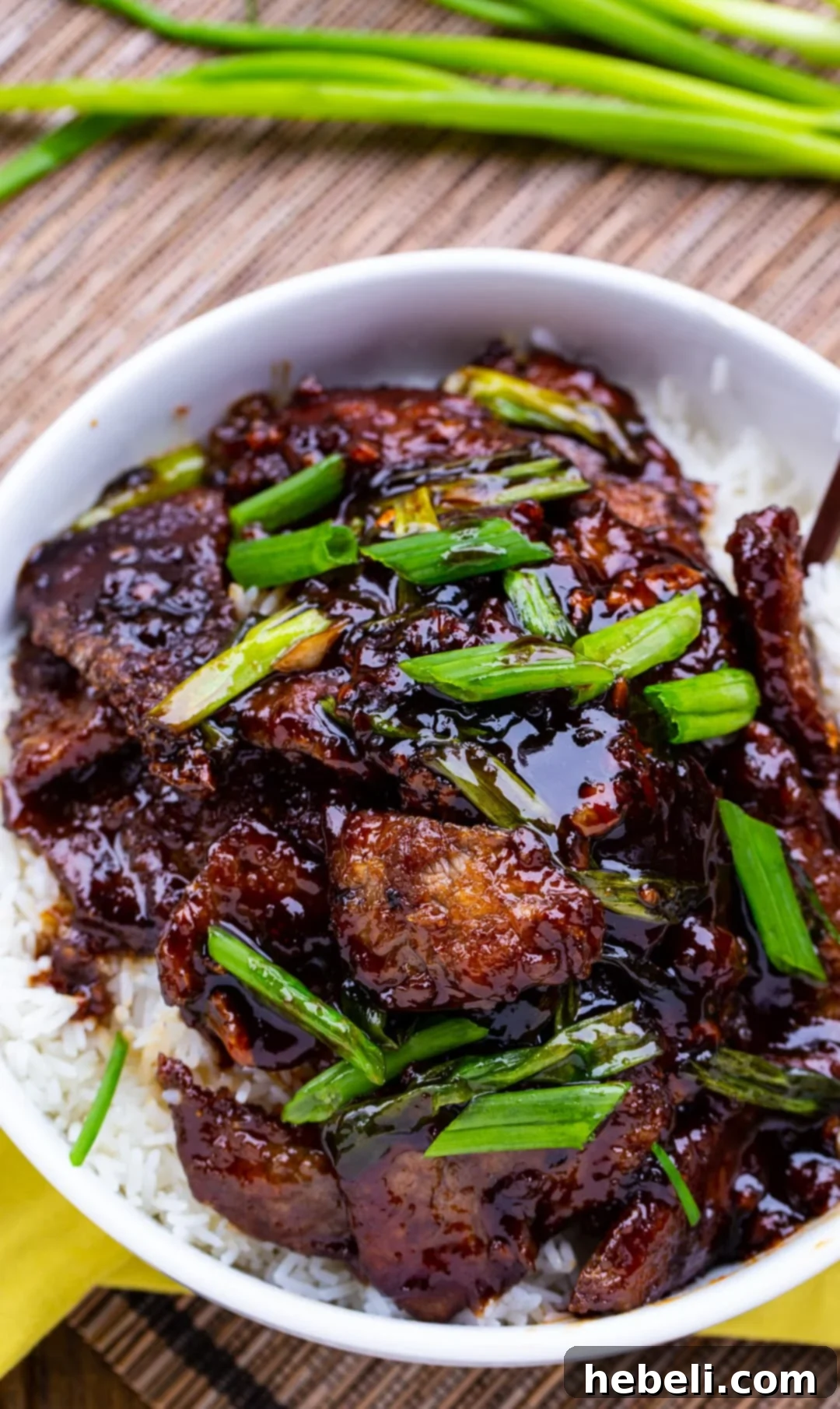 Close-up of crispy Mongolian Beef pieces coated in sauce, served with white rice.