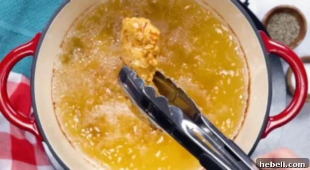 Frying the breaded chicken tenders in hot oil until golden brown and cooked.