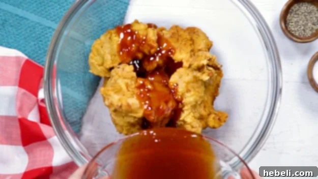 Pouring the homemade Honey Chipotle sauce over the freshly fried chicken tenders.