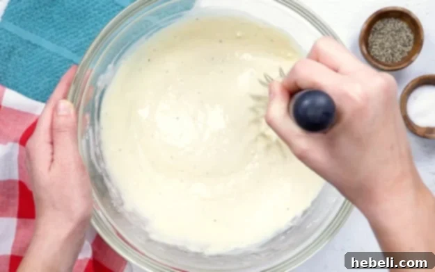 Whisking egg, milk, chicken broth, and seasonings to create the chicken batter.