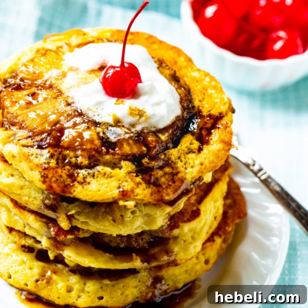Stack of Pineapple Upside Down Pancakes on a plate, garnished with a cherry.