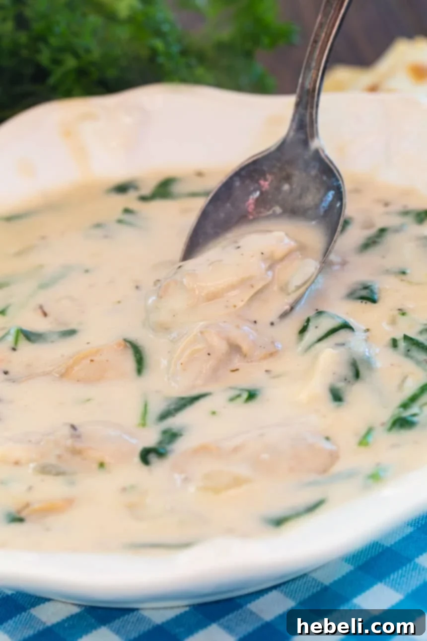 Oyster Stew: A Creamy Brie and Spinach Infusion 5 Spoon scooping up Oyster Stew with Brie and Spinach, showing the creamy texture and delicious ingredients.