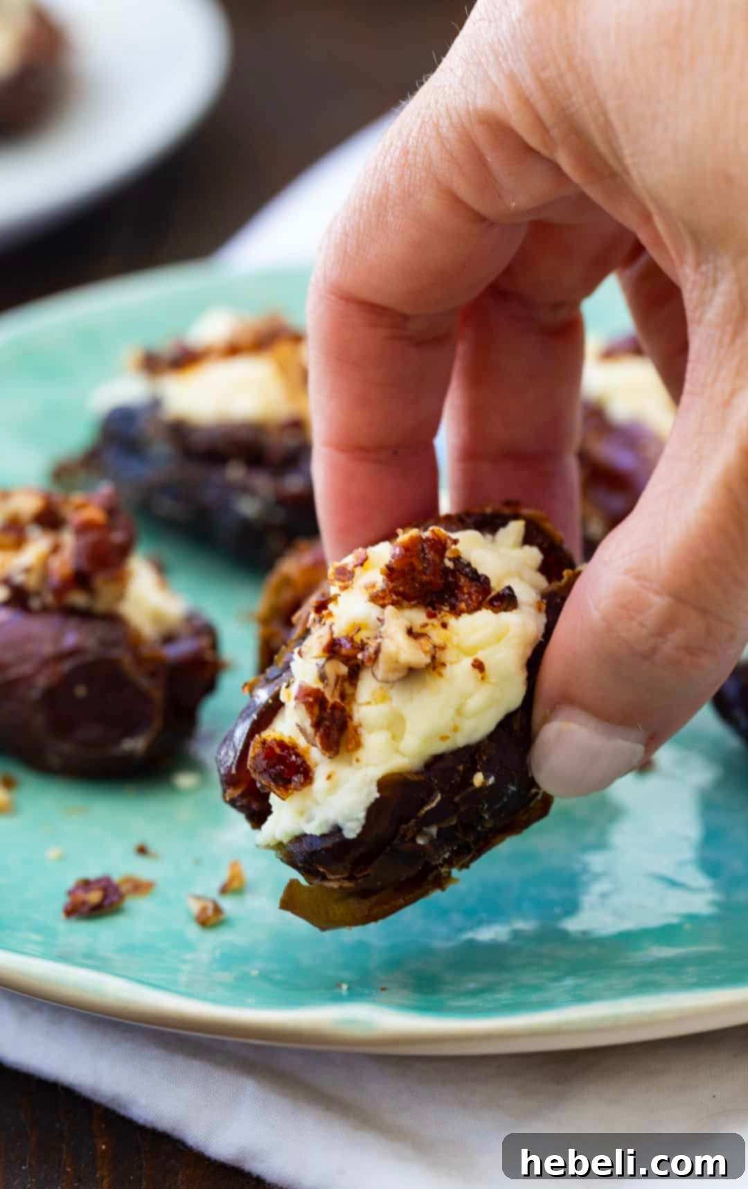 A hand picking up a delicious Whipped Feta Stuffed Date.