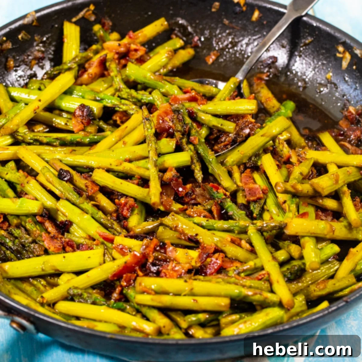 Smothered Asparagus in a skillet with bacon and onions.