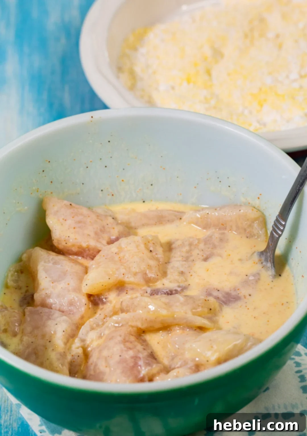 Catfish strips marinating in a bowl of buttermilk.