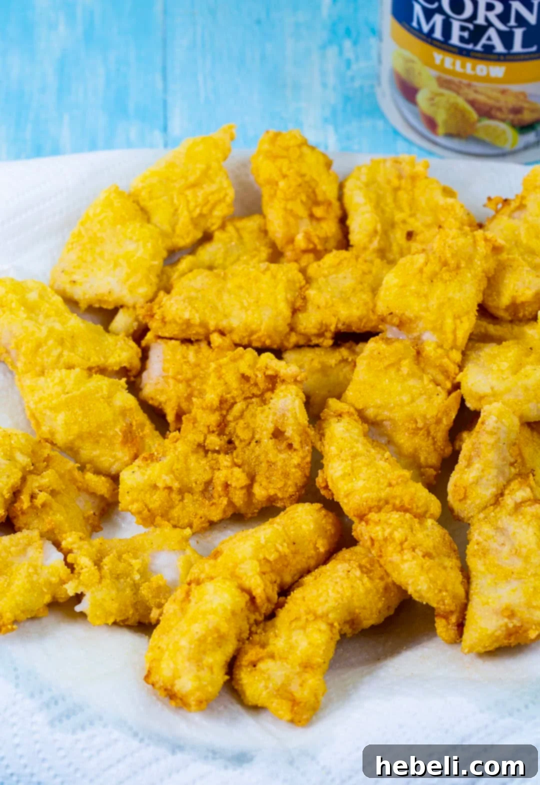 Perfectly fried catfish fingers draining on a paper towel-lined plate.