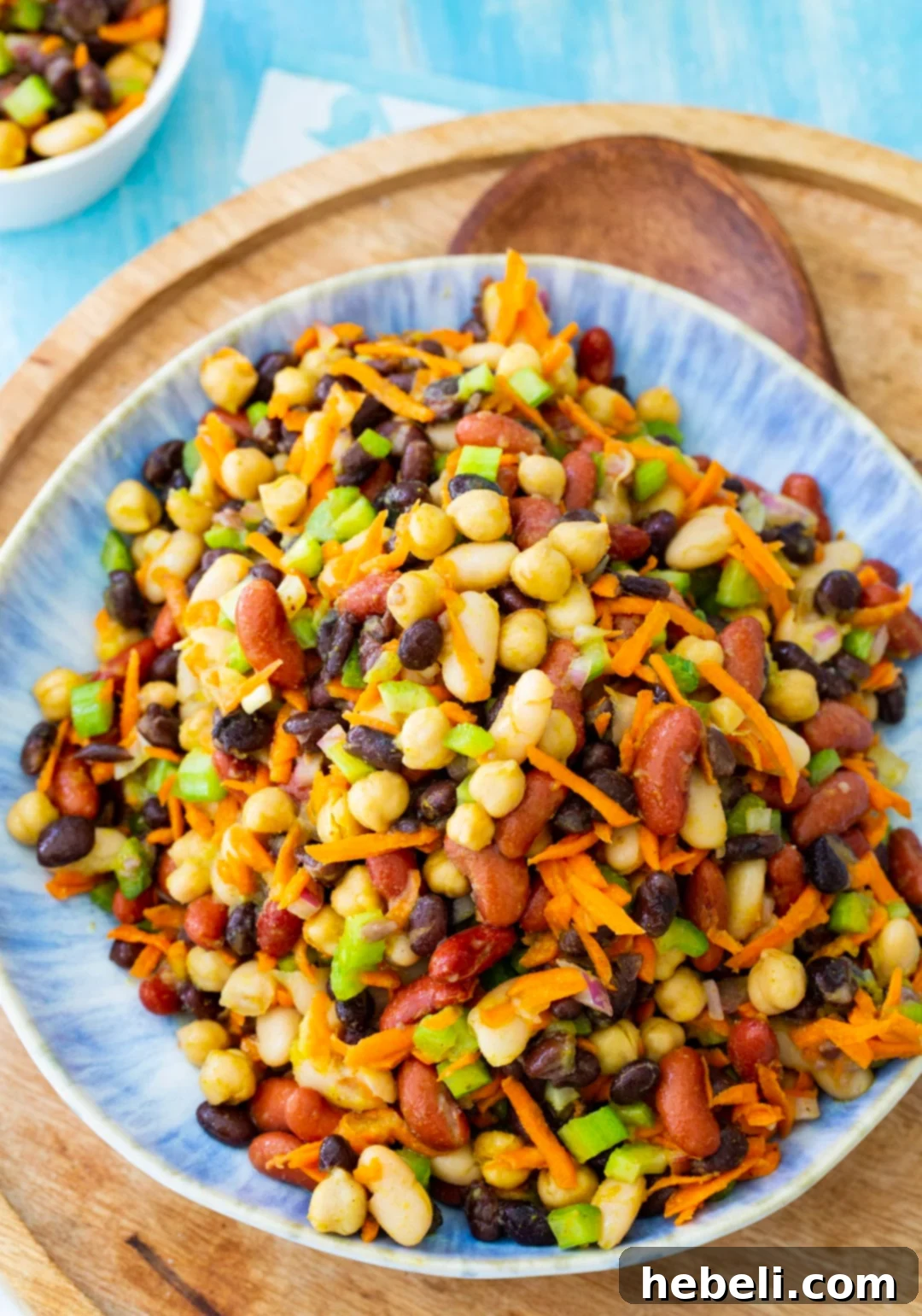 Sweet and Spicy Honey Curry Beans 4 Ingredients for Honey Curry Bean Salad, including beans, celery, carrots, and red onion, tossed together in a large mixing bowl.