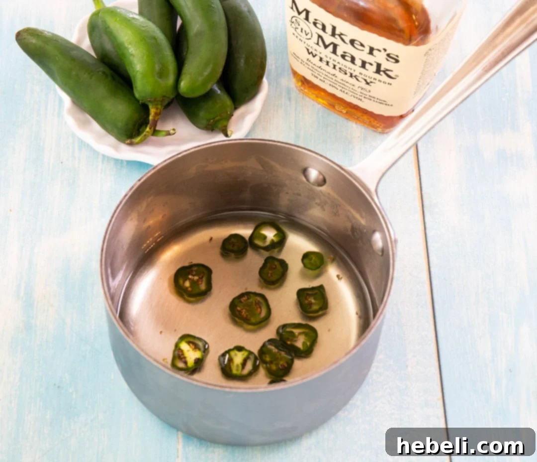 Southern Fire Julep 3 Making jalapeno simple syrup in a small saucepan with sliced jalapenos, sugar, and water.