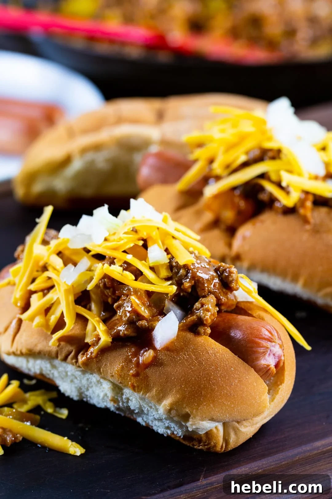 Sloppy Joe Hot Dog Recipe with Tangy Tomato Sauce 4 Hot Dogs topped with Sloppy Joe mixture on a wood serving board.