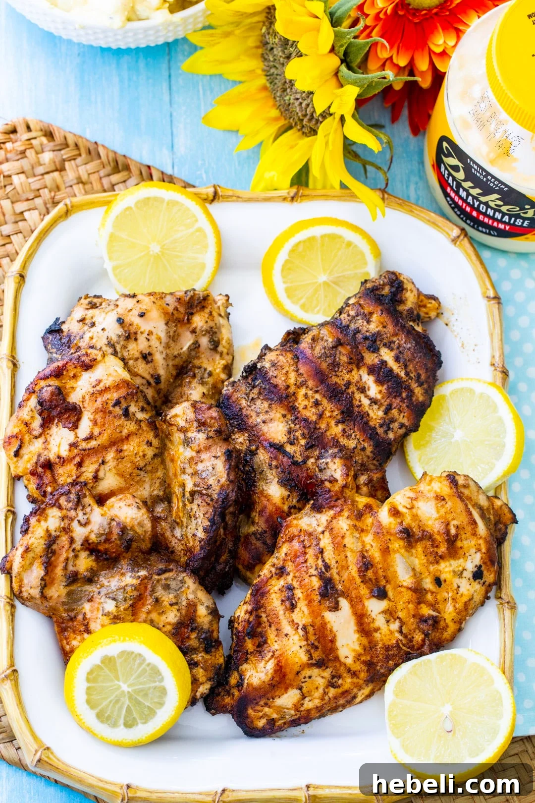 Mayonnaise Marinated Grilled Chicken on a serving platter with lemon slices and a jar of mayonnaise.
