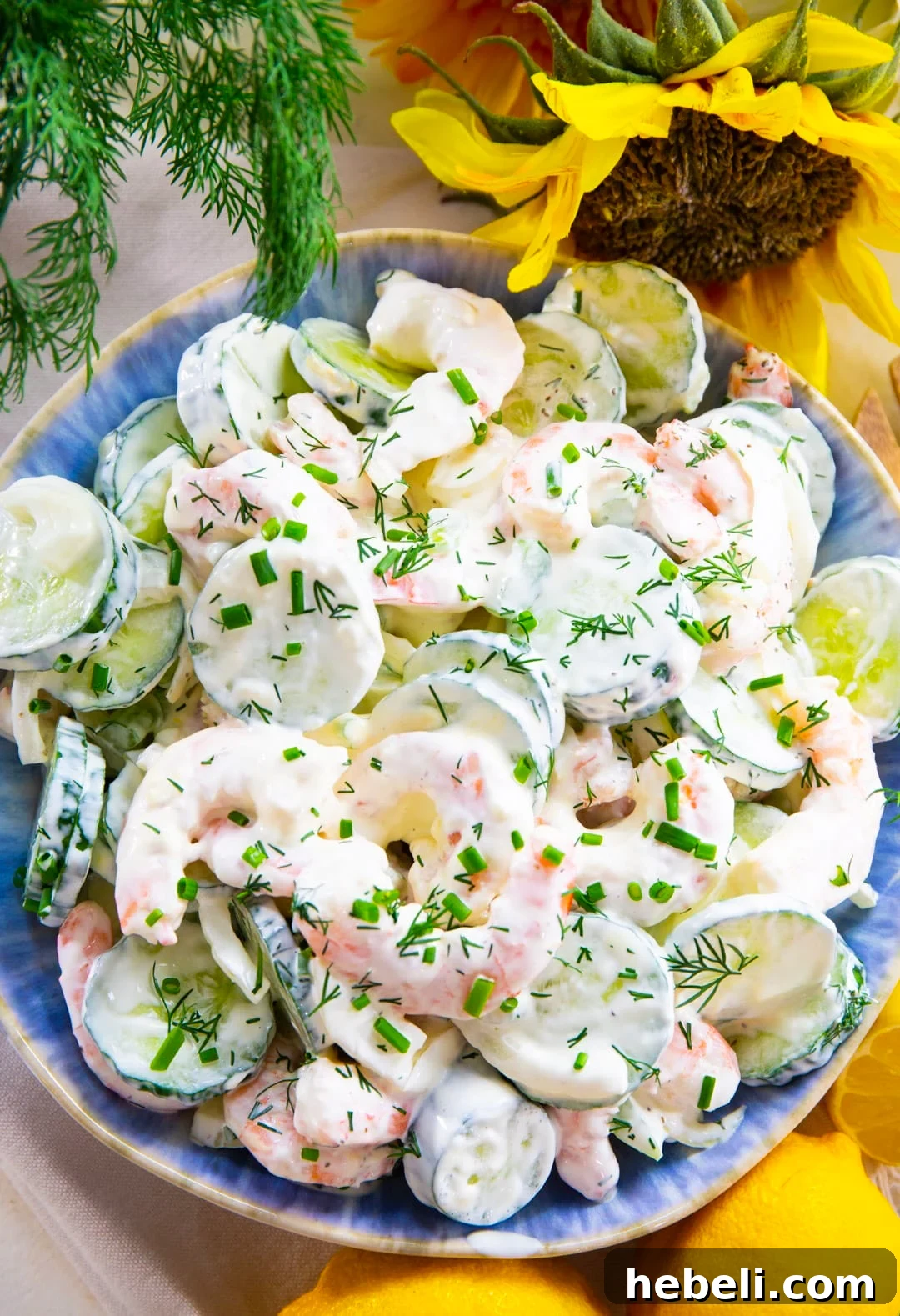 Refreshing Shrimp and Cucumber Salad with Zesty Dressing 4 Shrimp Cucumber Salad in a blue serving bowl surrounded by lemons and flowers.