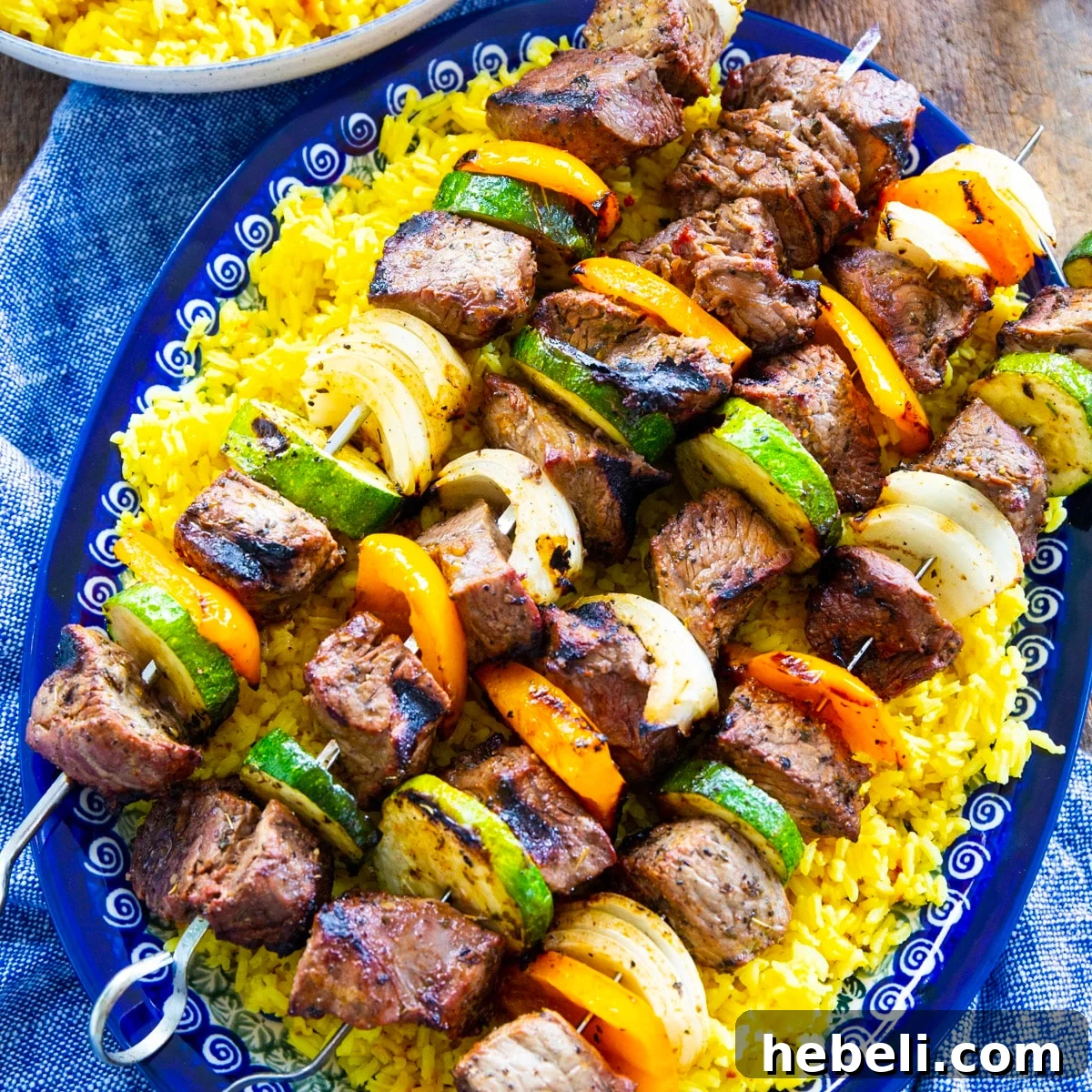 Garlic Marinated Beef Shish Kabobs on the Grill 2 Grilled Beef Shish Kabobs over yellow rice on a serving platter.