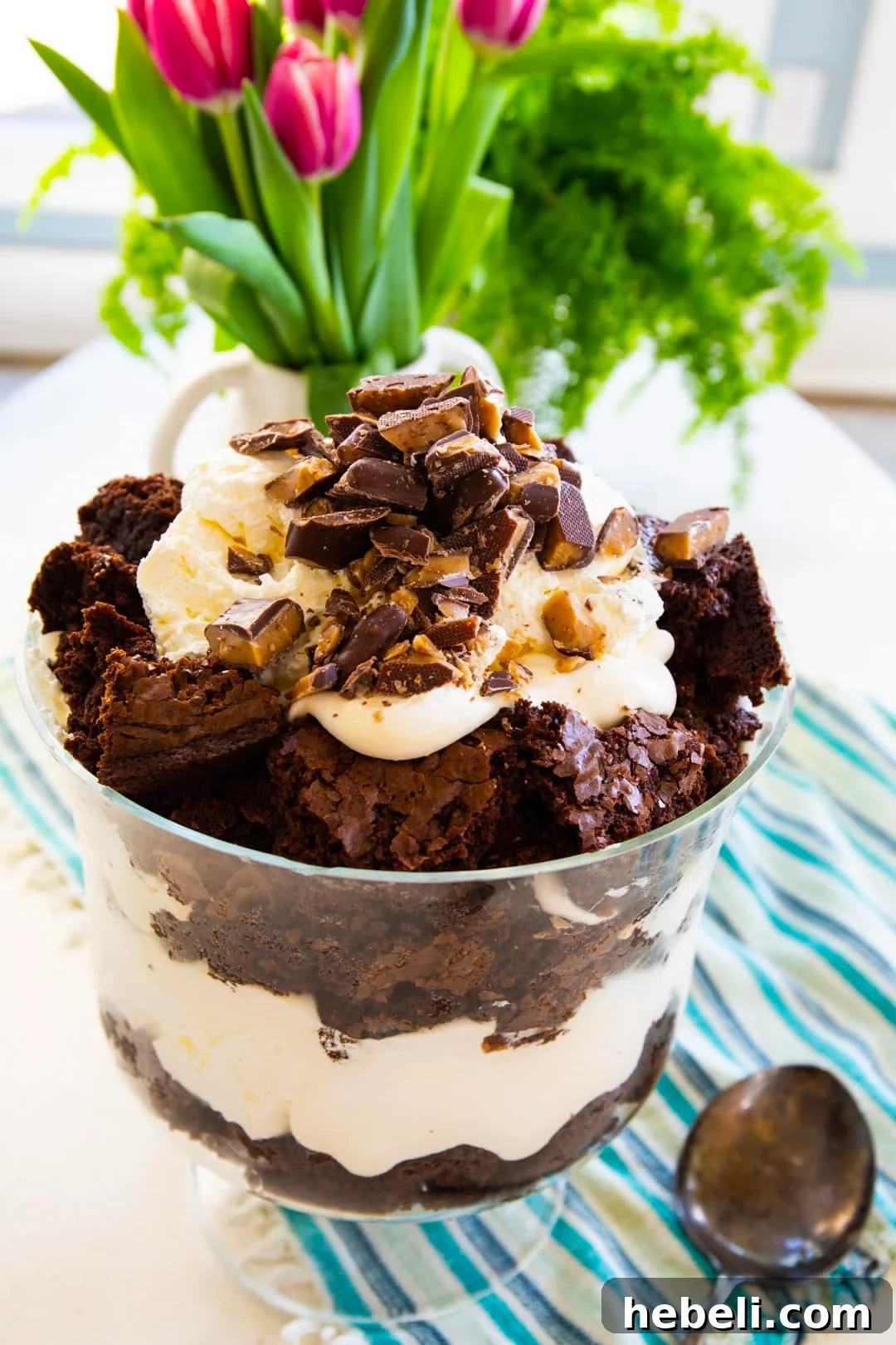 Brownie Trifle in a trifle bowl and tulips in background.
