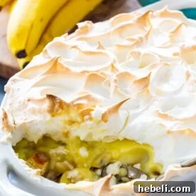 Banana Pudding with Meringue in baking dish with a serving scooped out.