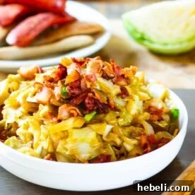 Cabbage in a bowl with plate of bratwurst in background.